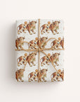 A gift box beautifully wrapped in Harlow Day cowboy wrapping paper, accented with a rustic jute twine string bow for a classic western nursery look.