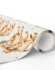 Roll of wrapping paper with golden cows and babies illustration on a light background.