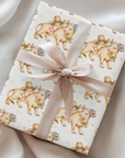 Gift wrapped in paper with darling cow and baby illustrations and tied in a pink ribbon.