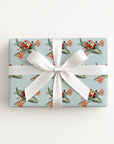 A rectangular gift box wrapped in a vintage-inspired Christmas wrapping paper featuring Santa flying a silver airplane with peppermint striped propellers on a light blue background.