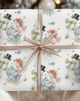 Hands holding a Christmas gift wrapped in vintage-style snowman baby boy wrapping paper with a blue baby carriage and a copper striped ribbon bow