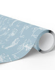 A roll of dusty blue wrapping paper with a white line-art pattern of whimsical carousel animals, shown on a clean white background.