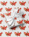 Wrapped gift tied with a white satin bow, displayed on matching wrapping paper featuring a little boy piloting a red airplane over a delicate navigation map with gold accents on an ivory background.