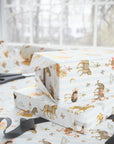 Stack of gifts wrapped in Carousel Menagerie wrapping paper featuring whimsical carousel animals on blue stripes, shown with matching gift wrap and ribbon.