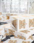 Pink and blue carousel wrapping paper with Parisian style merry go round animals and gold scrollwork., shown wrapped around gift boxes on a table with scissors and ribbon near a bright window.