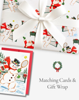Matching Christmas card and gift wrap featuring vintage illustrations of snowmen and Santa playing tennis, with a white gift bow and red envelope.
