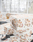 Ivory wrapping paper with a vintage style baby and elephant pattern, shown wrapped around gift boxes on a table with scissors and ribbon near a softly blurred window background.
