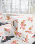 Gift boxes wrapped in paper featuring a little girl flying a pastel pink biplane over a delicate aviation navigation map on an ivory background, displayed with an open roll of matching wrapping paper, dark ribbon, and scissors.