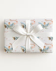 Baby Girl on Board airplane wrapping paper with a little girl aviator flying a vintage blue biplane with a pink banner on a soft white background.