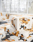 Western gift wrap with a cowgirl bride swinging a lasso on a palomino horse and a groom in a tuxedo and cowboy hat running, on a wrapped gift.