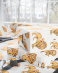 Ivory wrapping paper with a repeating pattern of storybook lions and children, shown wrapped around gift boxes on a table with scissors and a black ribbon in a bright indoor setting.