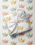 Gift wrapped in paper with pastel airplanes and girl pilot pattern, tied with a white ribbon.