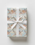 Upright gift wrapped in vintage-style twin baby shower wrapping paper with storks, a white satin ribbon and bow