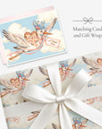 Twin girls stork card with matching twin girls stork gift wrap tied with a white satin bow, labeled Matching Card and Gift Wrap