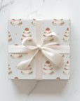Square gift wrapped in minimalist wedding cake wrapping paper with an ivory satin ribbon and bow on a white marble surface
