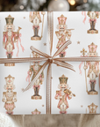 Hands holding a Christmas gift wrapped in vintage-style pink nutcracker wrapping paper with a copper striped ribbon bow