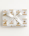 Gift wrapped in Palm Beach Carousel Wrapping Paper featuring flamingos, crocodiles, lions, carousel horses, and pastel carousel canopies.