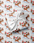Gift wrapped in vintage-style polo match Christmas wrapping paper with Santa, a snowman and a reindeer on ponies, tied with a white satin bow