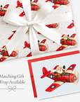 Vintage-style Santa pilot Christmas card in a red airplane with matching red airplane gift wrap, tied with white satin ribbon