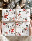 Hands holding a Christmas gift wrapped in vintage-style Santa and snowman tennis wrapping paper with a copper striped ribbon bow