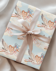 Twin girls stork wrapping paper on a gift with a blush ribbon resting on soft silk