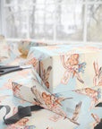 Stacked gifts wrapped in twin girls stork wrapping paper beside a sunny window