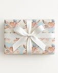 Twin girls stork wrapping paper on a gift tied with a white satin bow