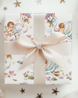 Gift box with a decorative pattern featuring swans and babies, tied with a beige ribbon on a white background.
