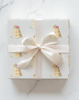 Square wedding gift wrapped in elegant ivory wedding cake wrapping paper with a cream satin bow on a white marble surface