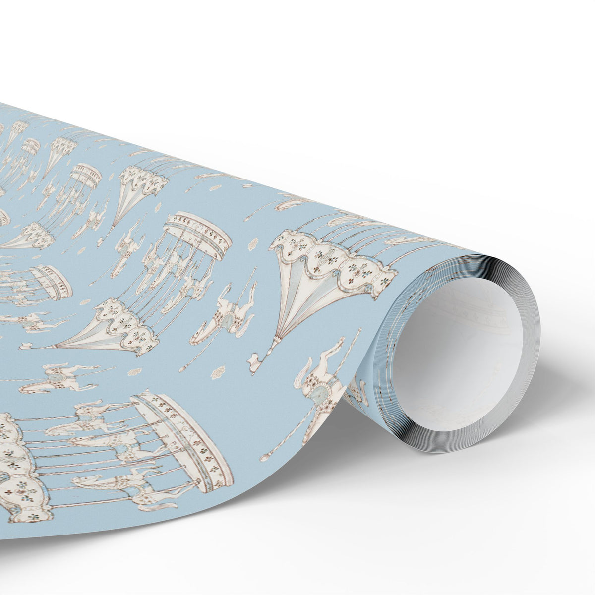 A roll of wrapping paper featuring a whimsical pattern of hot air balloons, carousel horses, and a rabbit on a light blue background, shown on a clean white studio background.