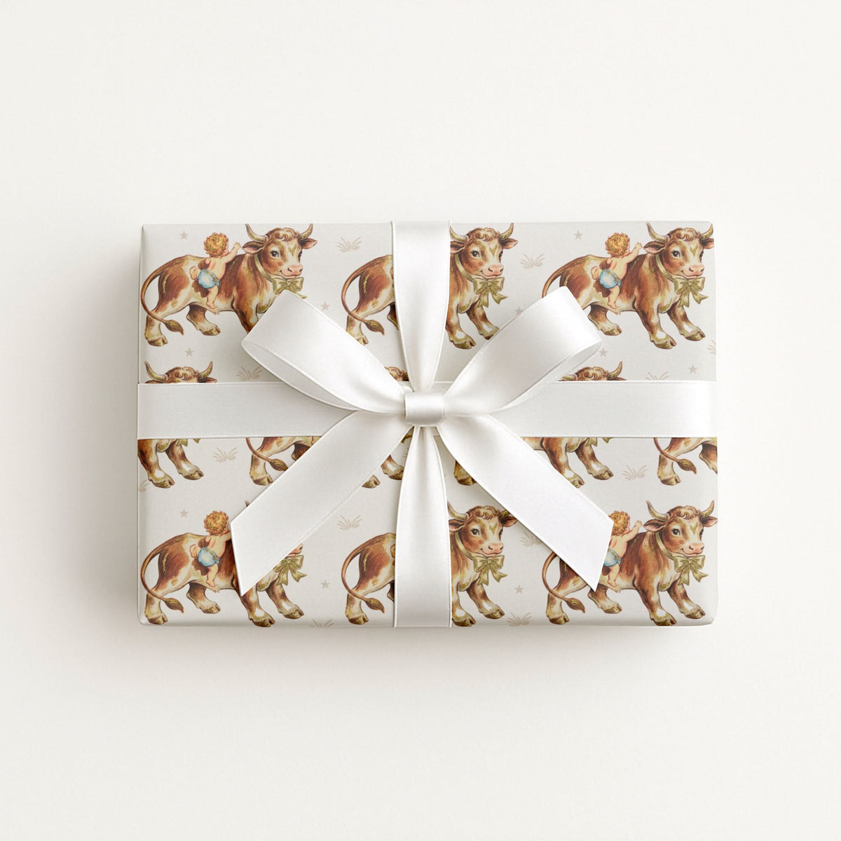 Gift box wrapped in a vintage baby paper featuring cowboy baby boys and gentle farm bulls on a ivory background.