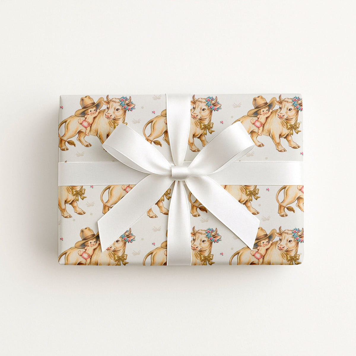 Gift box with a sweet baby and cow pattern with a white ribbon on a light background.