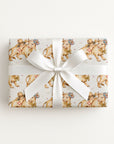 Gift box with a sweet baby and cow pattern with a white ribbon on a light background.