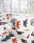 White wrapping paper with a colorful vintage airplane pattern, shown wrapped around gift boxes on a table near a window.