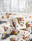 Christmas-themed wrapping paper with a festive print of Santa Claus, reindeer, and gold rockets, shown wrapped around gift boxes on a table with scissors in the background.