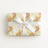 Gift wrapped with vintage baby and giraffe design with white ribbon on a yellow background.