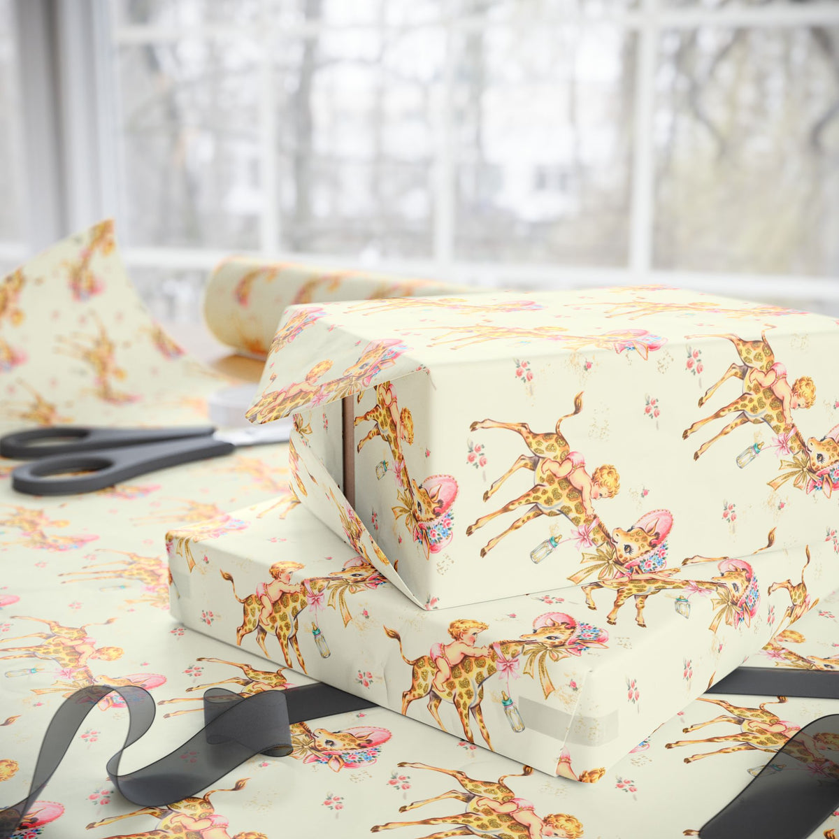 Yellow baby-themed wrapping paper with giraffes and little girls, shown wrapped around gift boxes on a table with scissors and ribbon near a bright window.