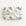 A rectangular gift box wrapped in ivory wrapping paper with a repeating pattern of vintage blue airplanes with shark mouth noses with gold accents, tied with a wide white satin ribbon and bow, on a plain white background.