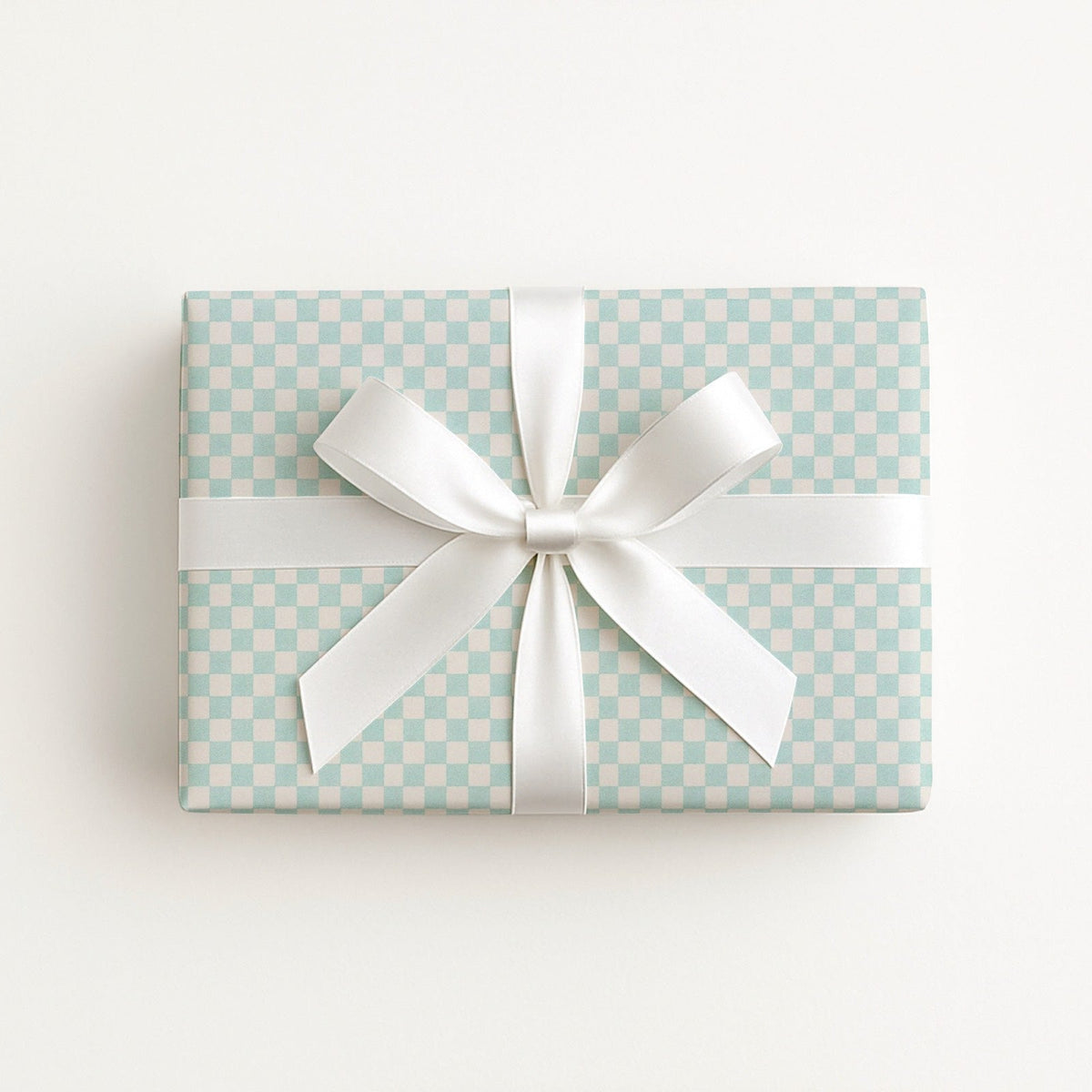 A rectangular gift box wrapped in aquamarine and off white checkered paper with a wide white satin ribbon tied in a bow, photographed from above on a clean white background.