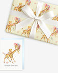 Giraffe baby shower wrapping paper on a gift tied with a satin bow beside a matching Welcome Little One greeting card