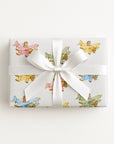 Gift box wrapped in a a decorative paper featuring biplanes in pastels on a light background