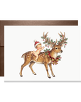 Vintage-style baby in a red Santa hat riding a spotted reindeer with antlers decked in holly, berries and ornaments, reindeer Christmas card