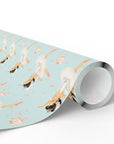 A roll of wrapping paper featuring a repeating pattern of ballerinas in white tutus on a light aqua background, shown on a clean white studio background.