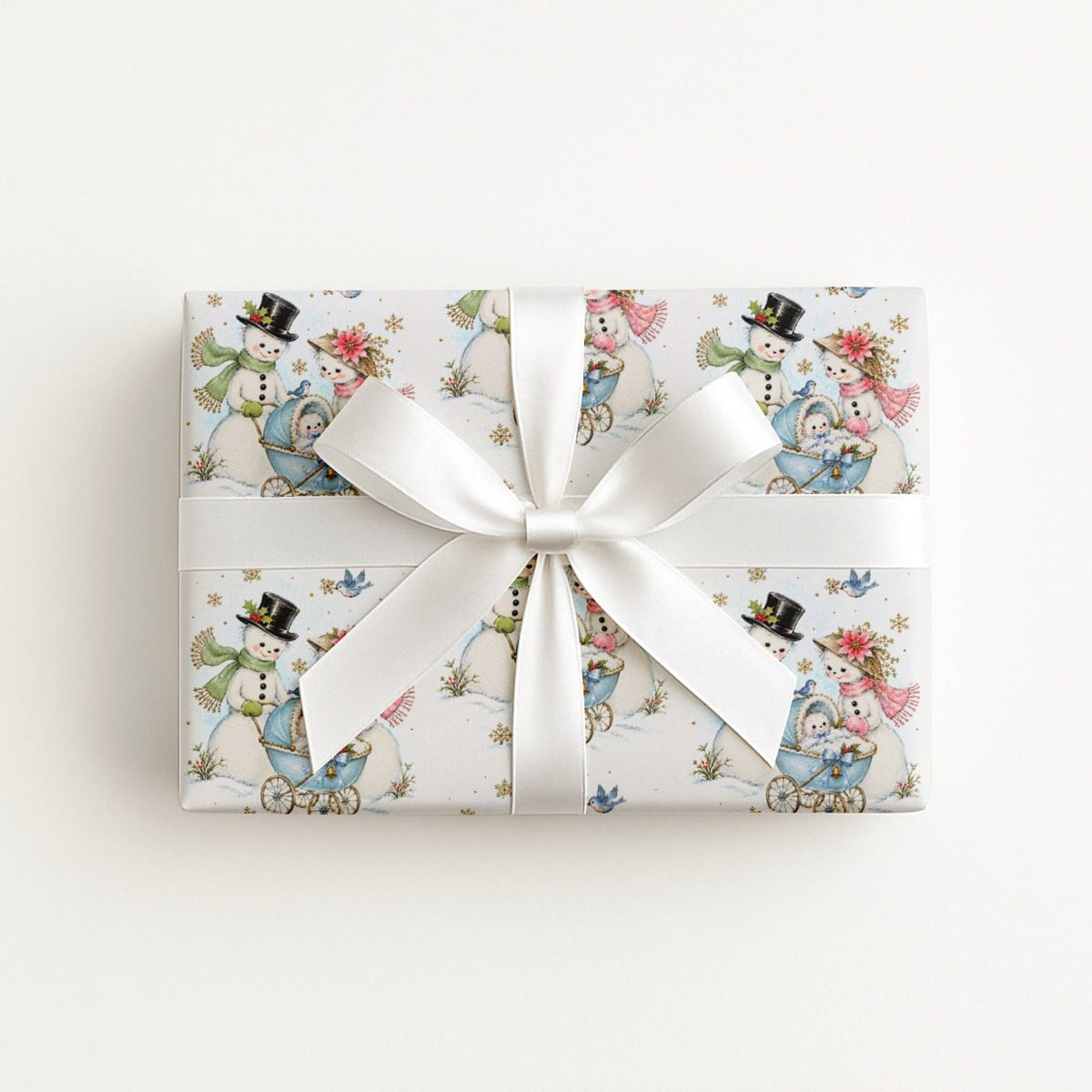 Flat lay of a gift wrapped in vintage-style snowman baby boy Christmas wrapping paper with a blue baby carriage and a white satin bow