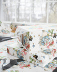 Stacked Christmas gifts wrapped in vintage-style snowman baby boy wrapping paper with a blue baby carriage on a wrapping table with scissors and black ribbon