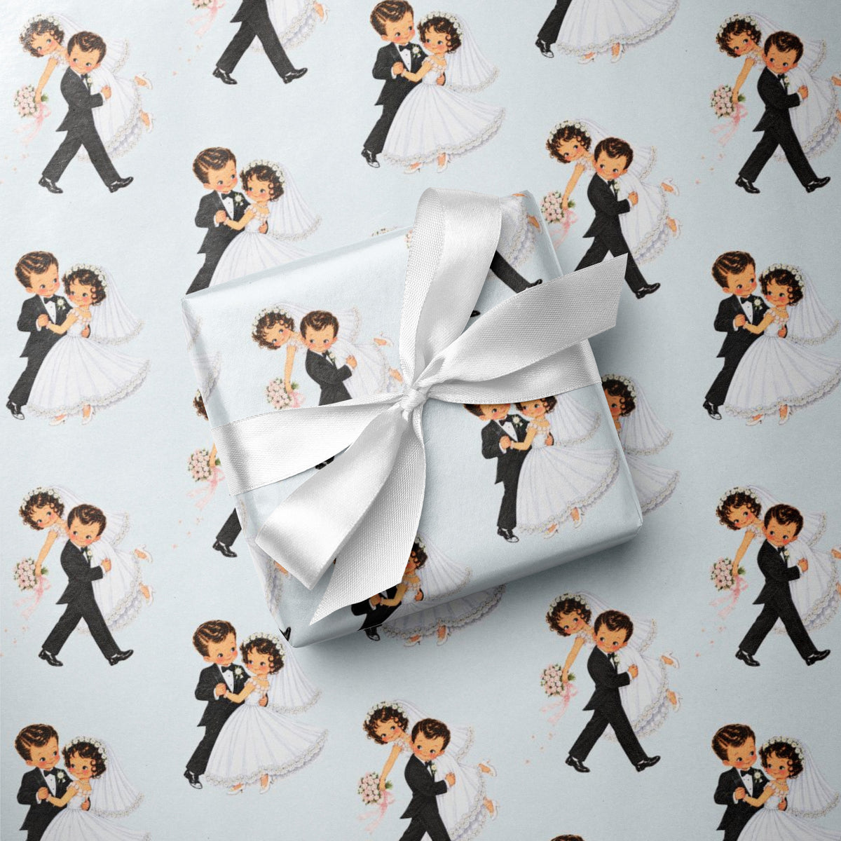 Gift with a satin ribbon resting on a repeating pattern of vintage-style dancing newlywed bride and groom on pale blue wrapping paper