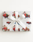 Flat lay of a gift wrapped in vintage-style snowman race car Christmas wrapping paper with a white satin bow