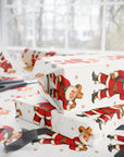 White wrapping paper with a vintage Christmas western style Santa Claus print, shown wrapped around gift boxes on a table with scissors and ribbon nearby.