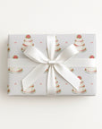 Flat lay of a gift wrapped in minimalist wedding cake wrapping paper with a large white satin bow