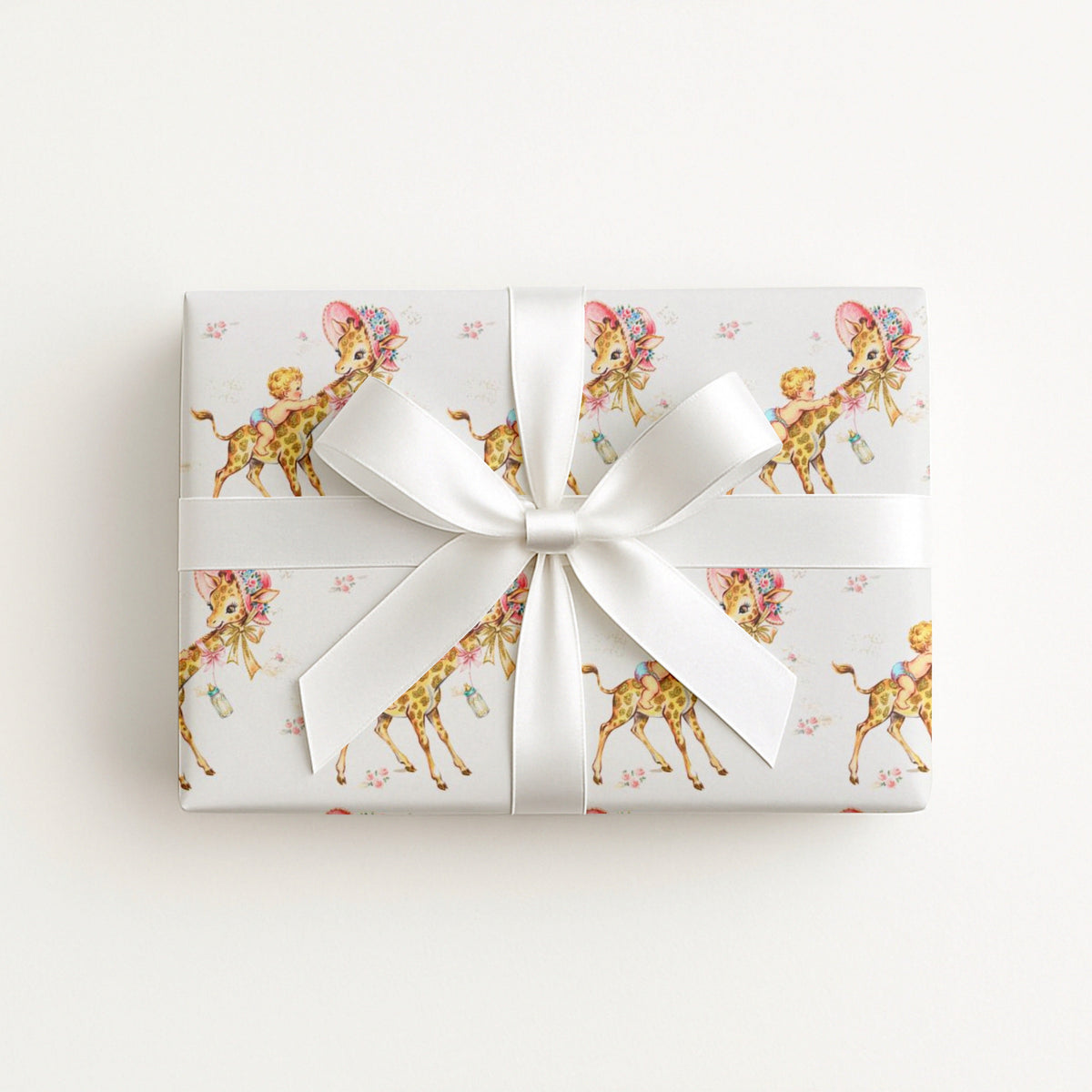 Vintage-style giraffe baby boy wrapping paper on a gift tied with a satin bow, baby boys riding giraffes in floral bonnets